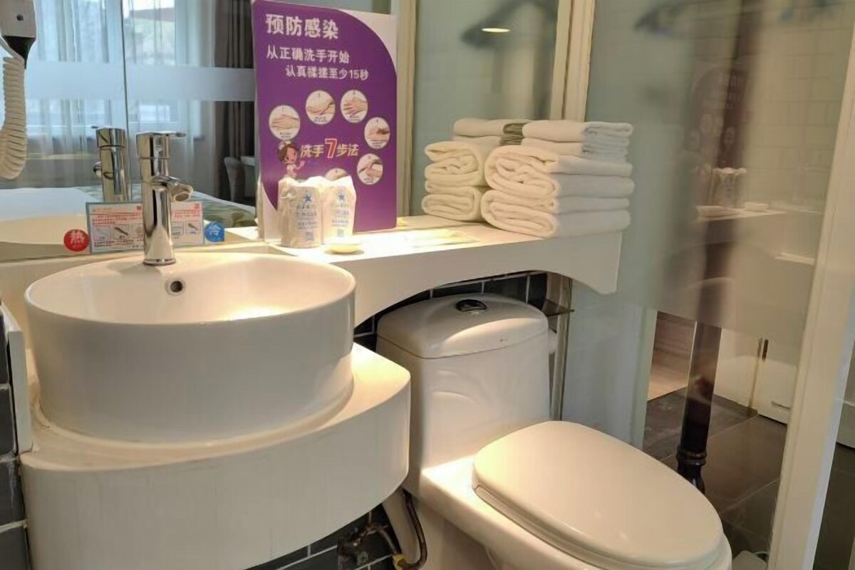 Ein Badezimmer mit Waschbecken, Toilette und einem Ablagebereich mit Handtüchern.