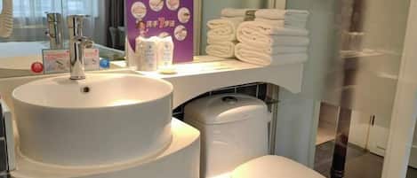 A bathroom with a sink, toilet, and a shelf with towels.