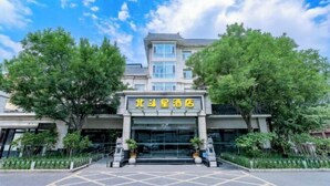 Ein Hotel Eingang mit einem Schild in chinesischen Schriftzeichen, einem überdachten Bereich und einem Parkplatz mit gelbem Gittermuster.