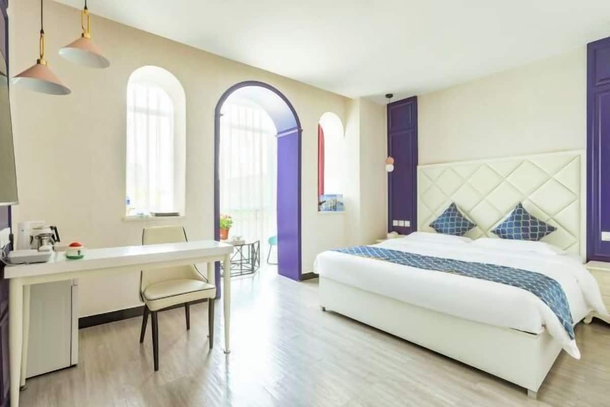 A bedroom with a bed, a desk, and chairs.