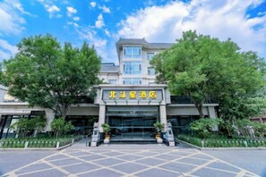 A hotel entrance with a signboard, a gated driveway, and a clear sky.