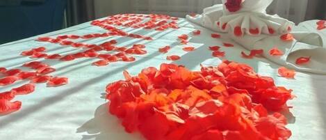 A bed with rose petals and a swan decoration.