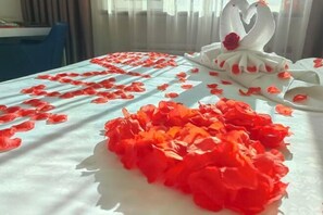 Ein Bett mit Rosenblättern und einer Schwan-Dekoration.