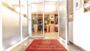 Ein Hotel mit rotem Teppich, Glastüren und einem sichtbaren Empfangsbereich.