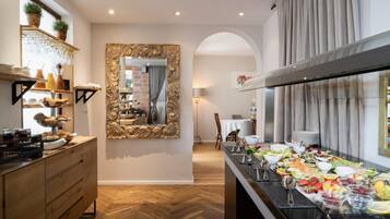 A buffet setup with a variety of food items, a mirror with ornate frame, and a wooden floor.