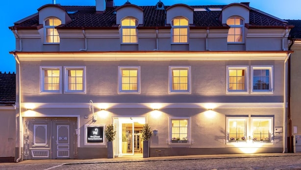 Ein zweistöckiges Gebäude mit einer symmetrischen Fassade, zahlreichen Fenstern und einem zentralen Eingang mit einem Schild.