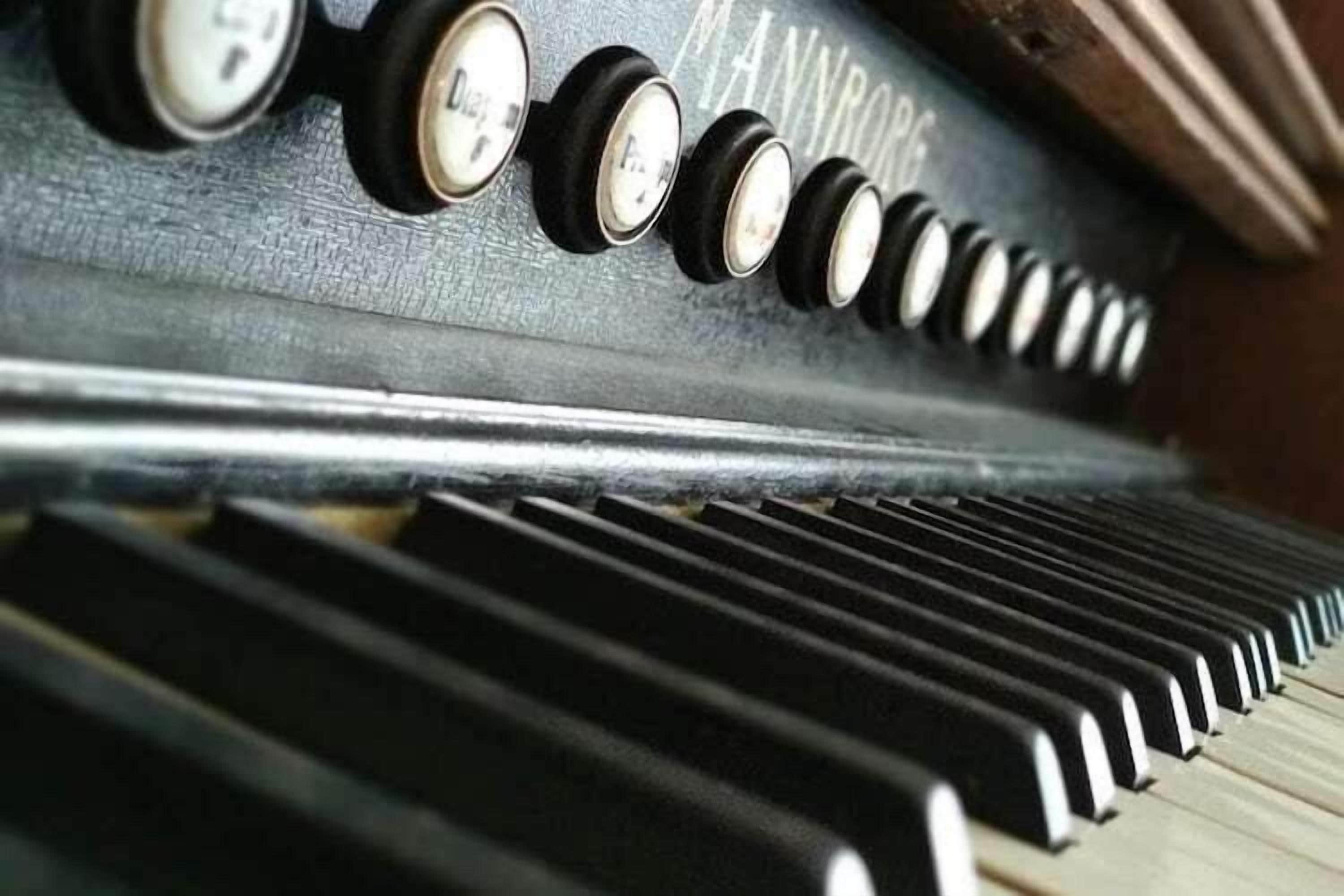 Primer plano de un teclado de piano con teclas negras y blancas, y una fila de pedales de piano.