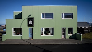 Un edificio moderno y verde con un letrero que dice "SJÁVAR BORG", indicando una cafetería o restaurante.