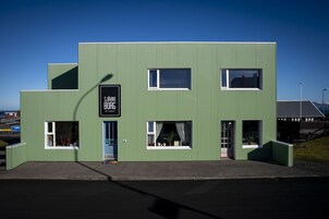 Un edificio moderno y verde con un letrero que dice "SJÁVAR BORG", indicando una cafetería o restaurante.