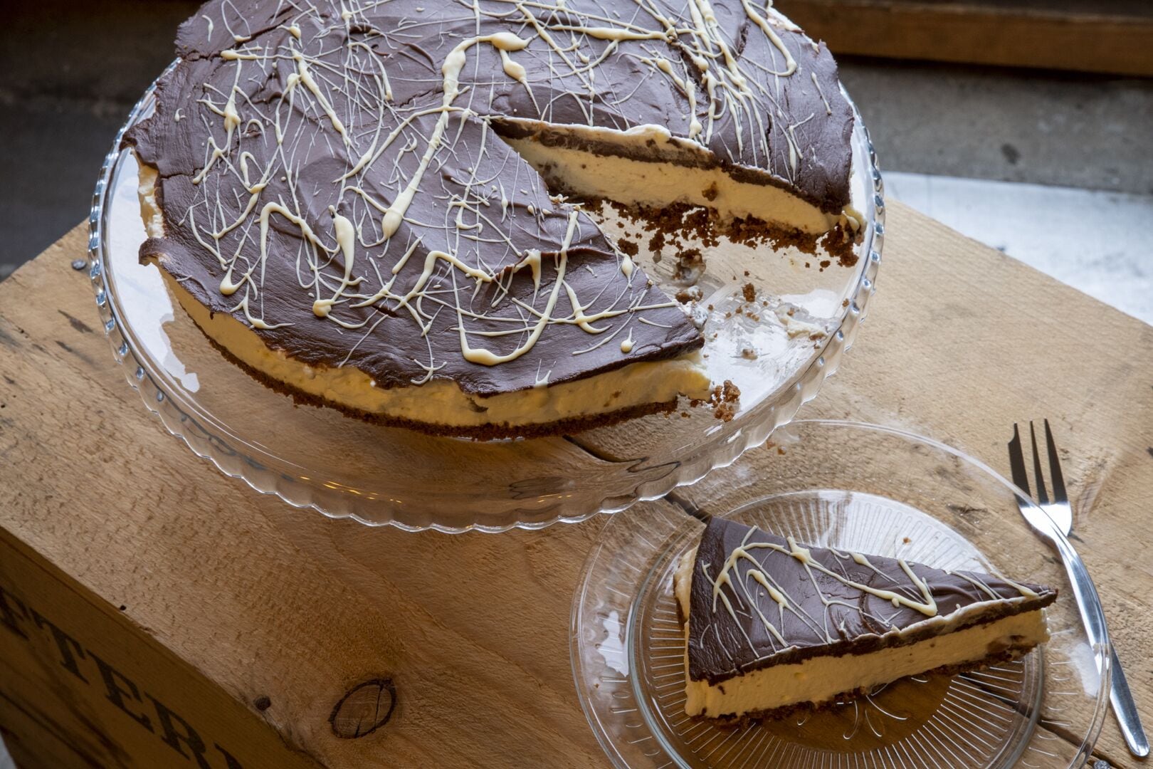 Un pastel de chocolate con una porción cortada, sobre una tabla de madera.
