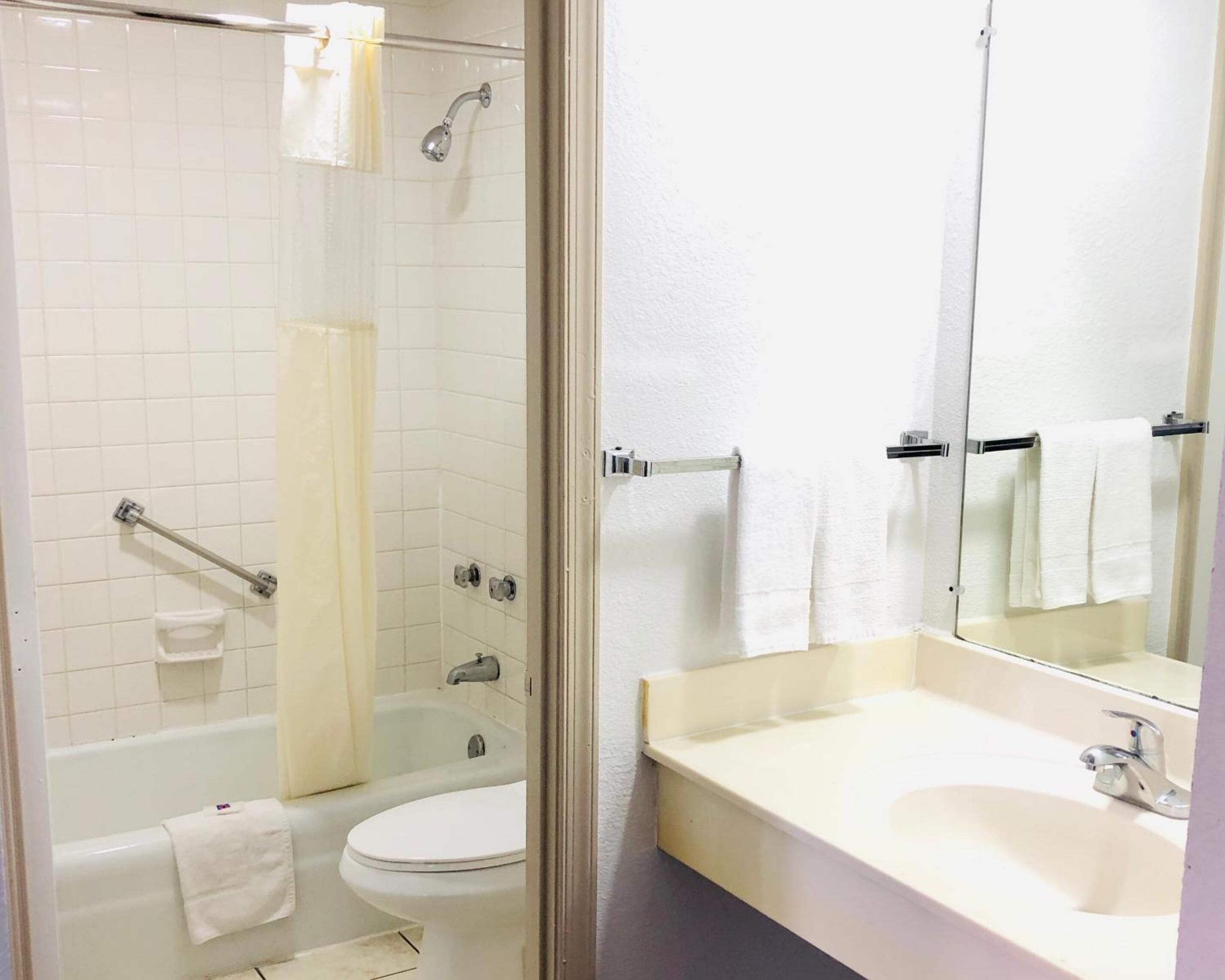 A bathroom with a glass-enclosed shower, a bathtub, a toilet, and a sink with a mirror.