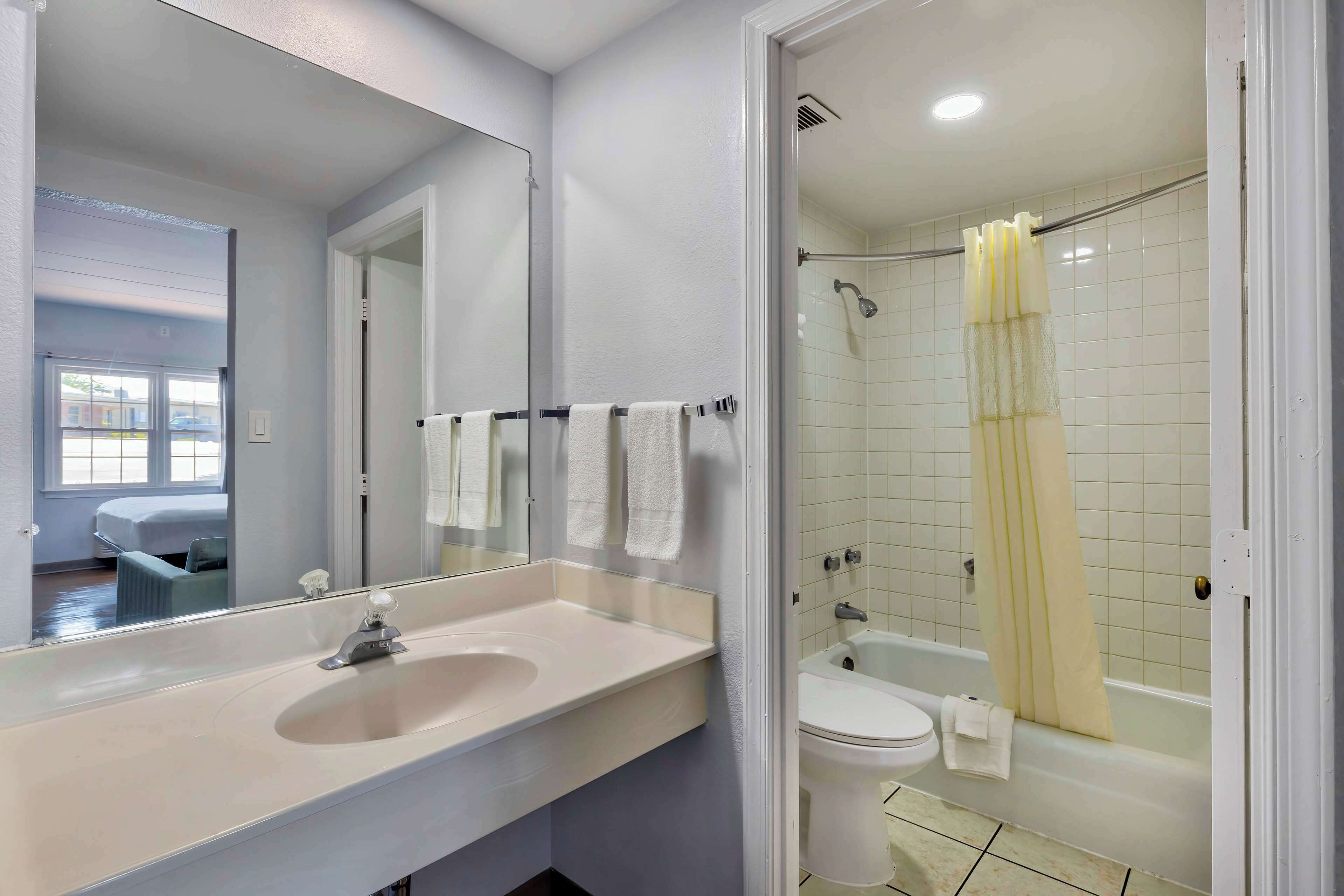 A bathroom with a sink, mirror, toilet, and shower.