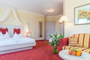 A hotel room with a bed, a sofa, a lamp, a vase with flowers, and a fruit bowl. - Hotel Wachau (Melk)