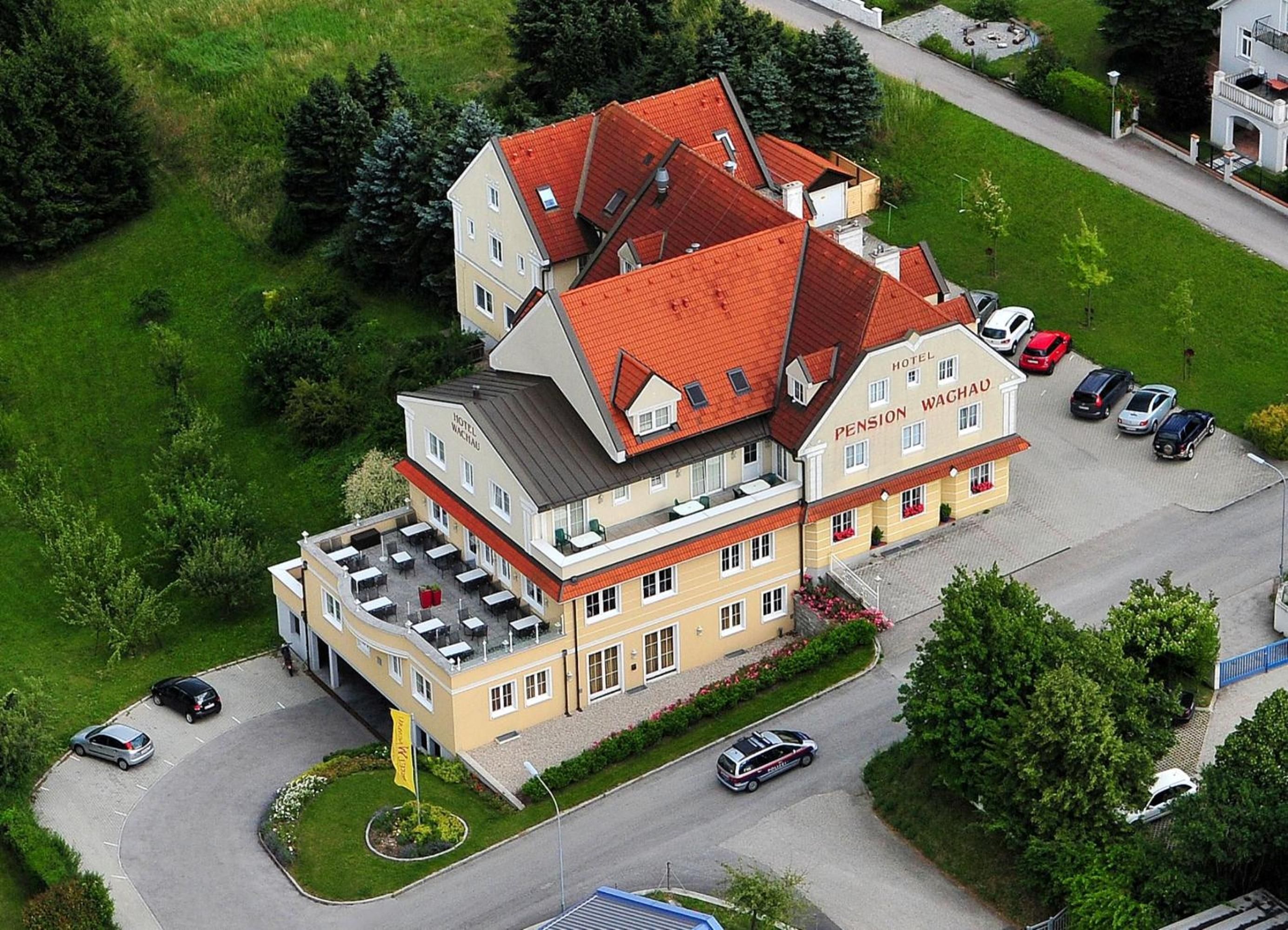 Ein mehrstöckiges Gebäude mit rotem Dach, Parkplatz und einer Hotel-Flagge.