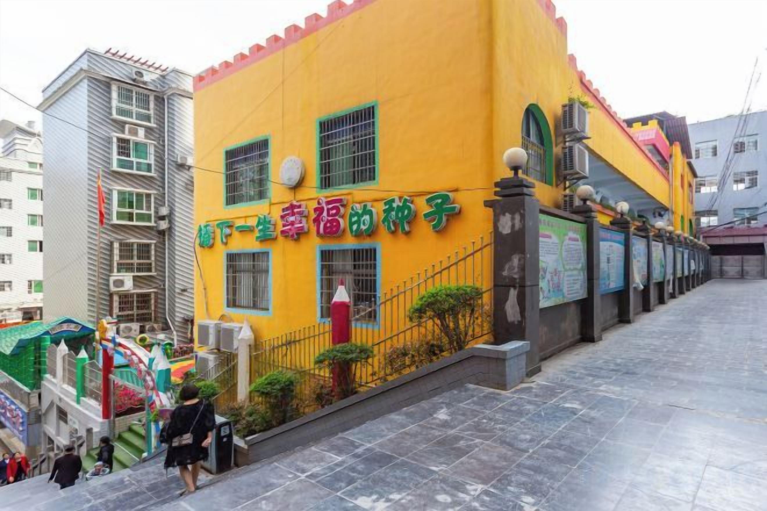 A yellow building with signage, a staircase, and a paved walkway.