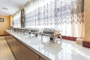 A buffet setup with multiple serving stations, a long counter, and a patterned wall. - Wujiang Hotel (Yanhe)