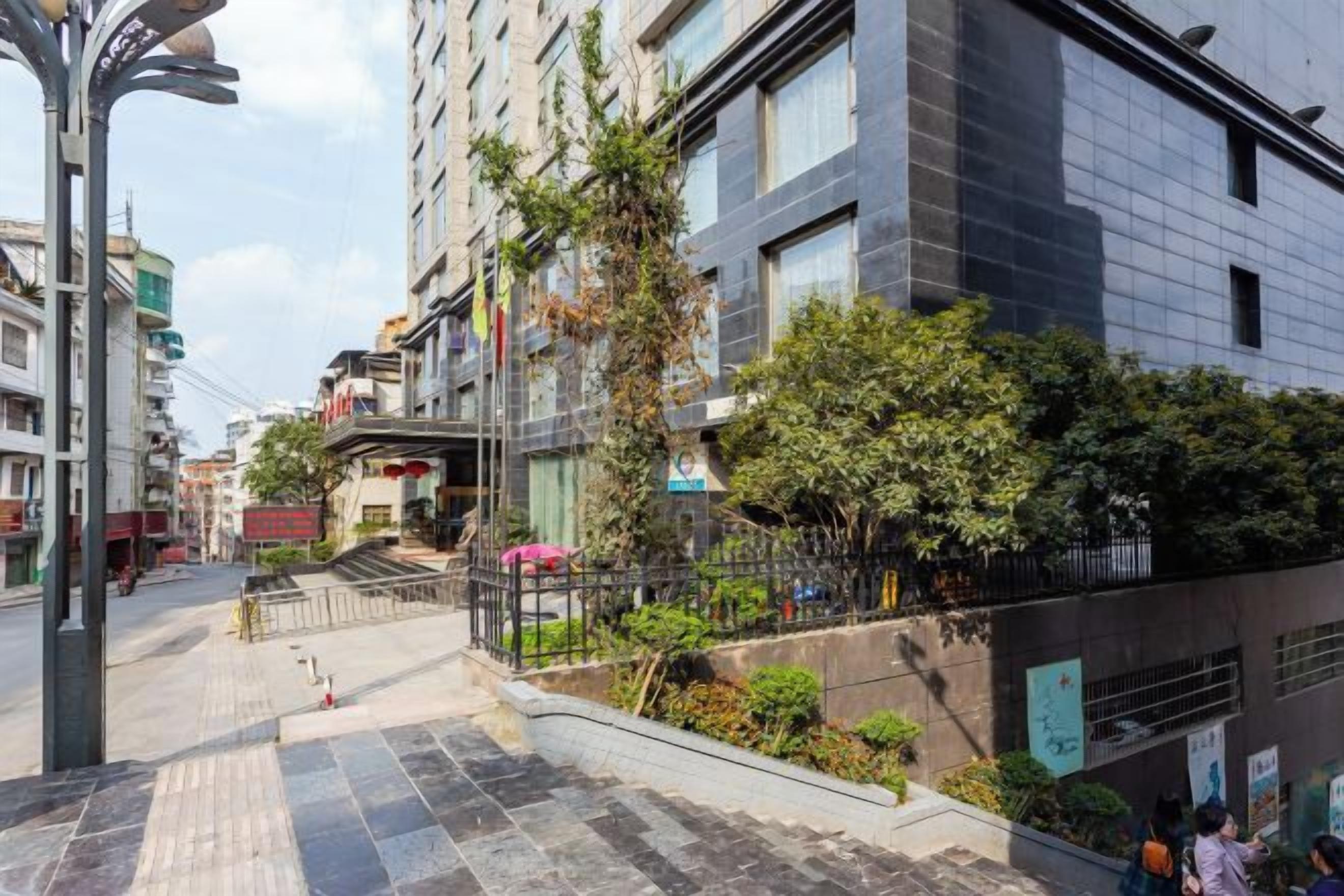 A multi-story building with a paved walkway and greenery.