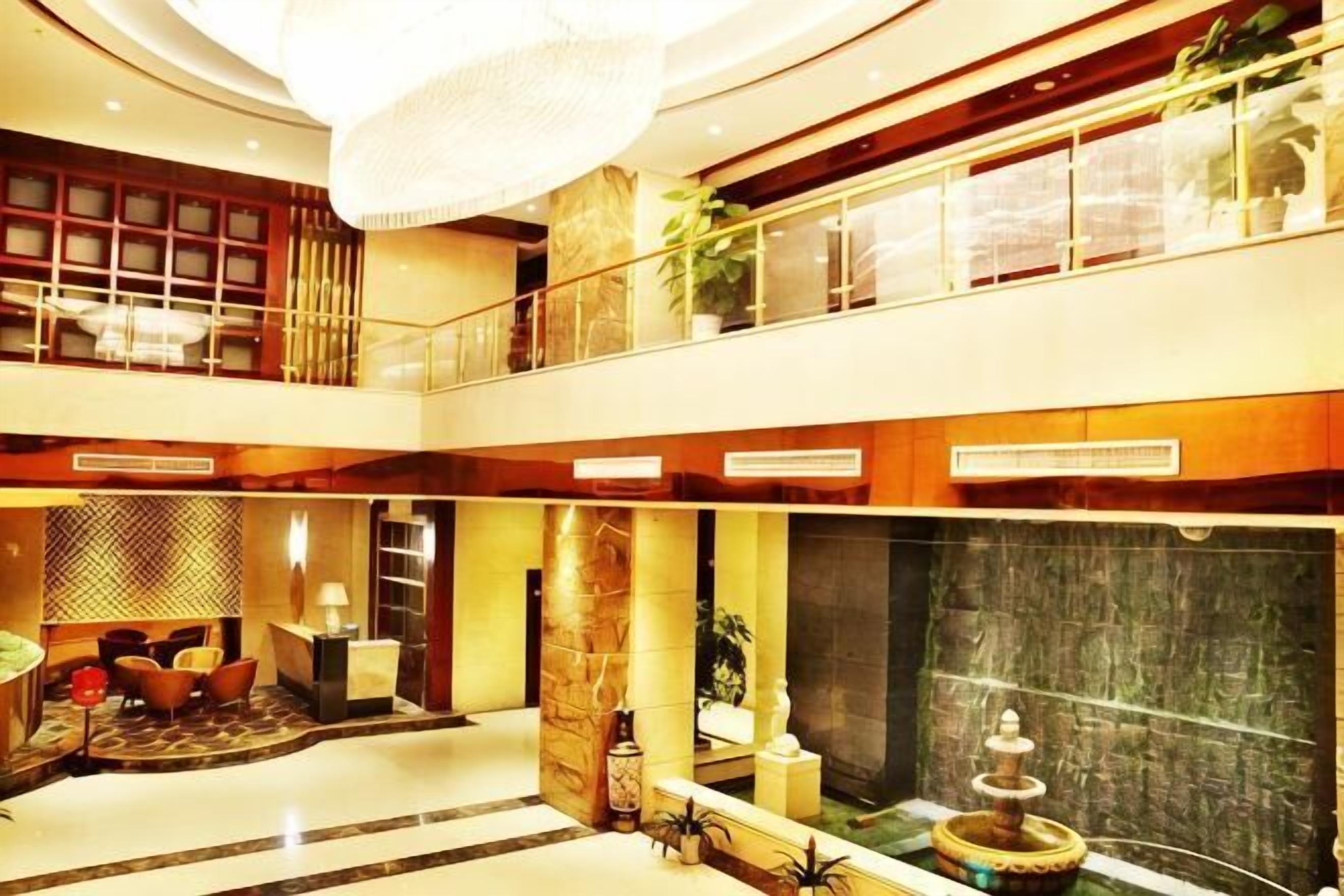 Un espacioso vestíbulo de hotel de varios niveles, con una gran araña, una fuente y zonas de estar.