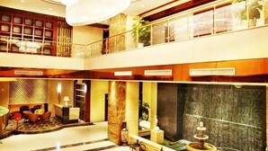 A multi-level hotel lobby with a grand chandelier, a fountain, and seating areas.