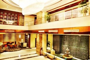 Un espacioso vestíbulo de hotel de varios niveles, con una gran araña, una fuente y zonas de estar.