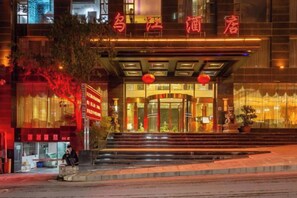 A hotel entrance with a red neon sign, a staircase leading up to the door, and a large window on the right. - Wujiang Hotel (Yanhe)