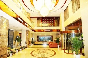Un vestíbulo de hotel con mostrador de recepción, zona de estar y una gran lámpara de araña.