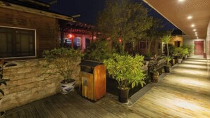 Eine Holzterrasse mit Blumentöpfen und einem überdachten Gang.