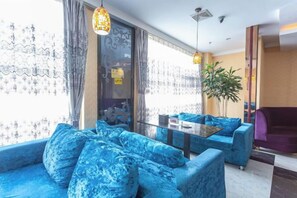 A modern hotel lobby with blue sofas, a glass coffee table, and a large plant. - Wujiang Hotel (Yanhe)
