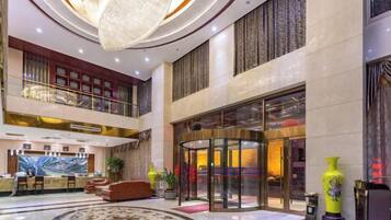 Een hotellobby met een receptiebalie, een zithoek en een groot rond vloerontwerp.