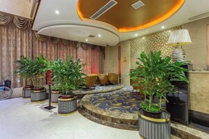 Un hall con una zona de estar circular, plantas en macetas y una alfombra estampada.