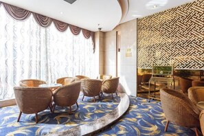 A hotel room with a curved blue carpet, wicker furniture, and patterned wall decor. - Wujiang Hotel (Yanhe)