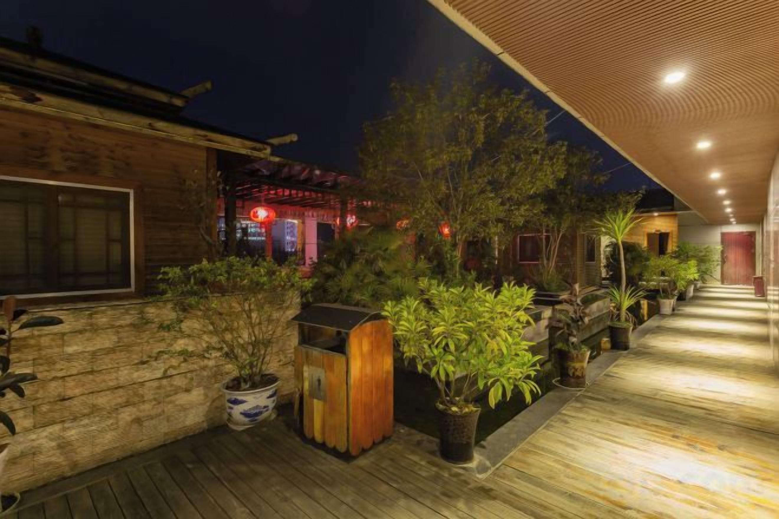 A wooden deck with potted plants and a pathway leading to a building with traditional architecture.