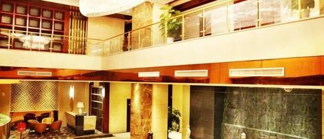 A multi-level hotel lobby with a grand chandelier, a fountain, and a seating area.