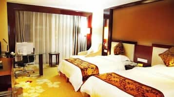 Habitación de hotel con dos camas, un escritorio, una silla, una mesita y una ventana con cortinas.