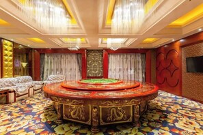 Una habitación con un área circular alfombrada, un conjunto de sofás y una pantalla grande en la pared.