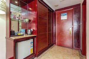 Un pasillo de hotel con un refrigerador, un espejo y una puerta con un letrero.