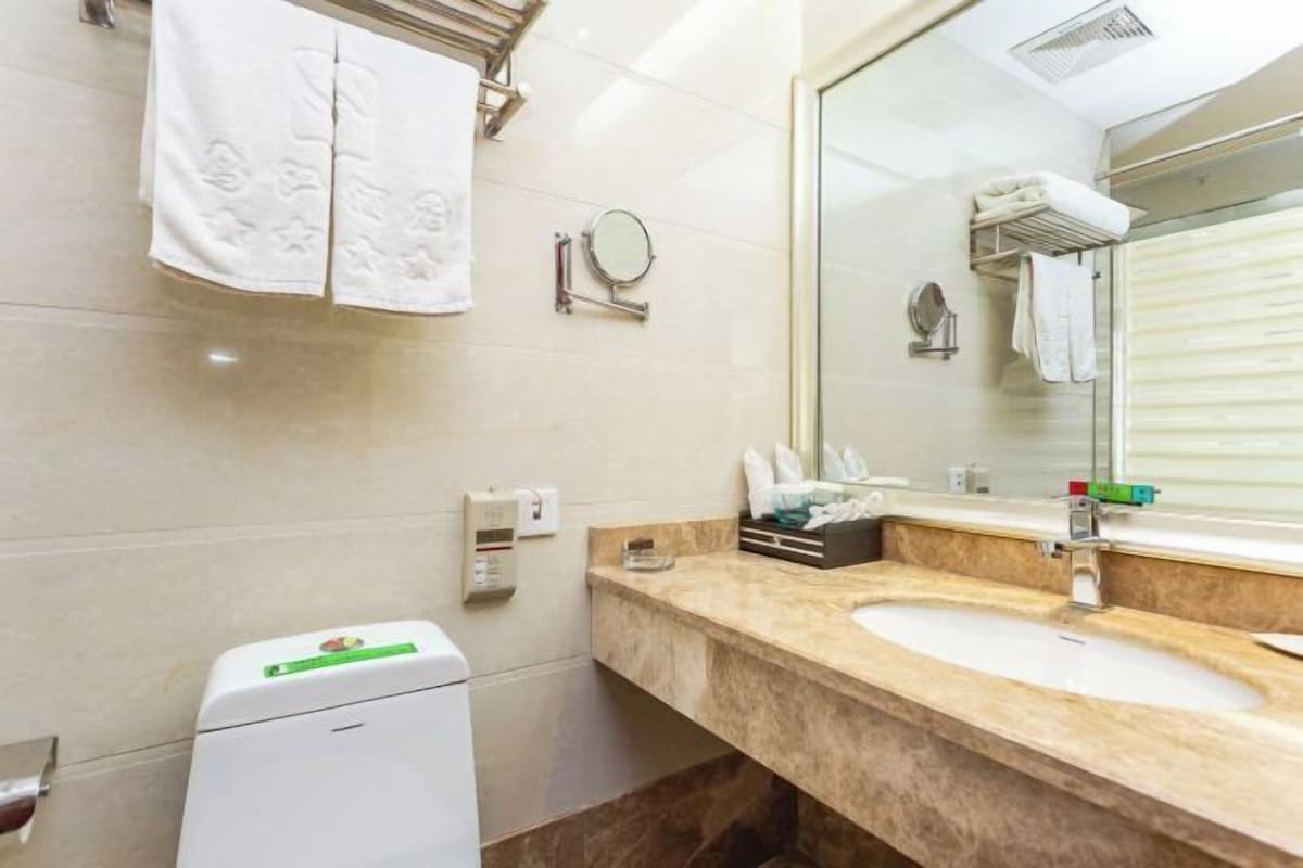 A bathroom with a sink, mirror, towel rack, and a small trash bin.