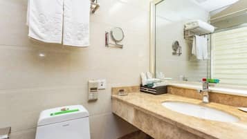 Un baño con lavabo, espejo, toallero y un pequeño cubo de basura.
