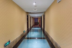 A hotel corridor with a blue-tiled floor, a visible exit sign, and a door at the end. - Wujiang Hotel (Yanhe)