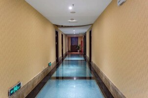 Un pasillo de hotel con piso de azulejos azules, una señal de salida visible y una puerta al final.