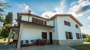 A two-story house with a patio, outdoor furniture, and a stone pathway. - Villa Leonardo (Sarteano)