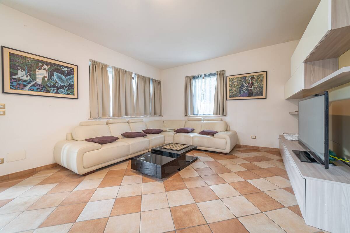 A living room with a beige sofa set, a coffee table, and a flat-screen TV.
