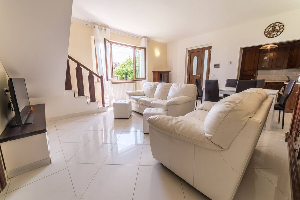 A modern living room with a sofa, ottoman, and a TV on a stand.