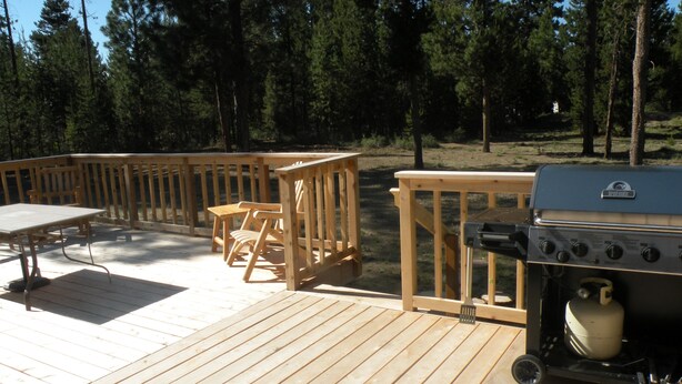 A wooden deck with a grill and seating area. - The Cozy Cabin LaPine (La Pine)