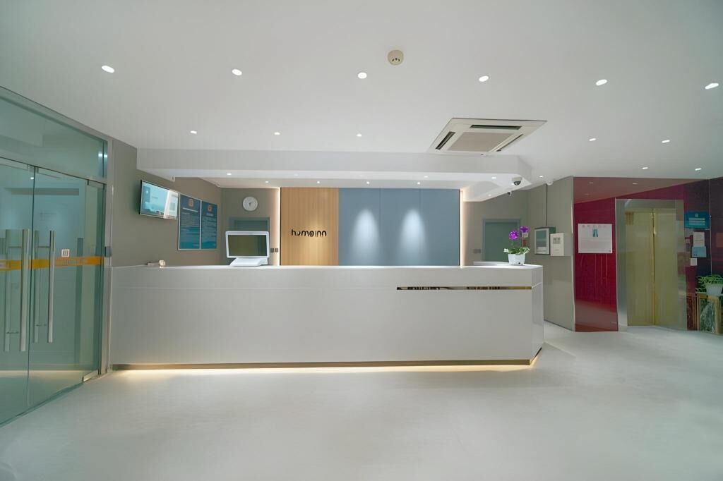Un espace d’accueil au design moderne, comprenant un comptoir d’accueil, une horloge et un écran numérique.
