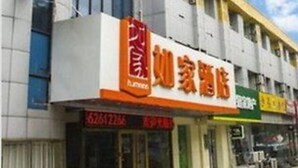A hotel with a prominent sign, multiple storefronts, and a clear sky.
