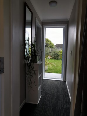 A hallway with a door leading to a garden. - Geyser Lookout BnB (Rotorua)