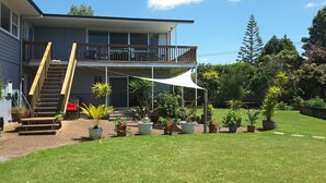 A two-story building with a balcony, a covered patio area, and a well-maintained lawn with potted plants. - Geyser Lookout BnB (Rotorua)