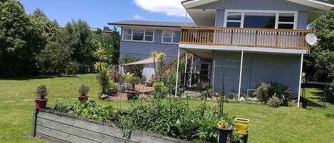 Une maison moderne à deux étages, dotée d’un balcon, d’un jardin clôturé et surplombant un ciel d’un bleu éclatant.