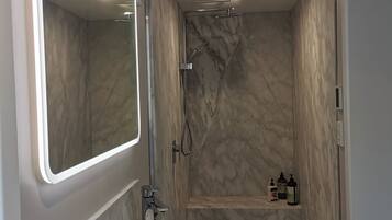 A modern bathroom with a white sink, a large mirror, and a shower area.